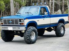 a blue and white truck parked in front of trees