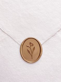 a wax stamp with a flower on it sitting on a piece of white parchment paper