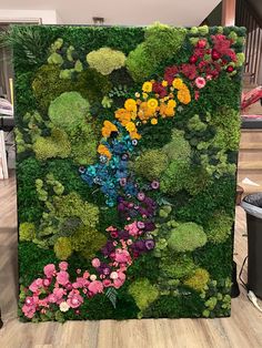 a large piece of art made out of moss and flowers is on display in a room