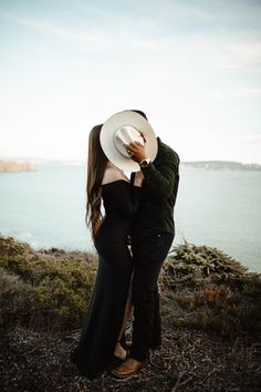 a man and woman standing next to each other near the ocean