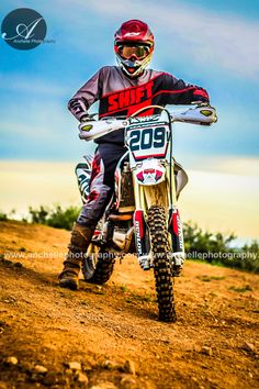 a person on a dirt bike in the middle of some dirt and blue sky with clouds