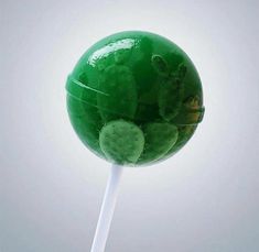 a green lollipop on a white stick with cactuses in the top and bottom