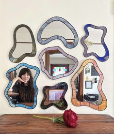 a woman is sitting in front of several mirrors on the wall with a rose next to it