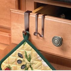 an oven door handle is hanging from the cabinet drawer with a pot holder on it