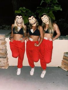 three women with masks on their faces standing next to each other in front of a wall