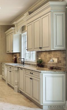 a kitchen with white cabinets and marble counter tops