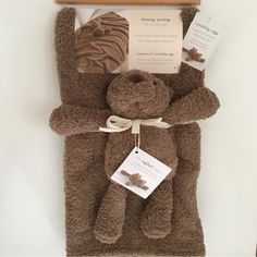 a brown teddy bear laying on top of a bed next to a wooden hanger