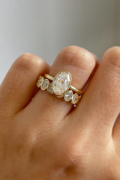 a woman's hand holding a diamond ring with three stones on the middle finger