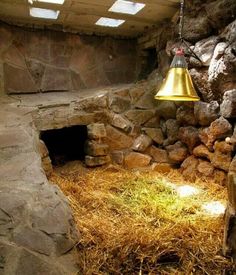 a light that is hanging from the ceiling in a room with stone walls and dry grass