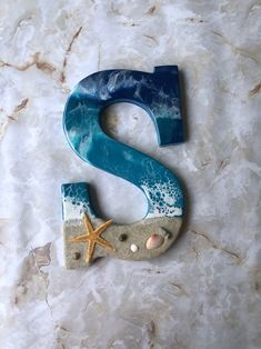 the letter s is made out of clay and sand with starfish on it's side