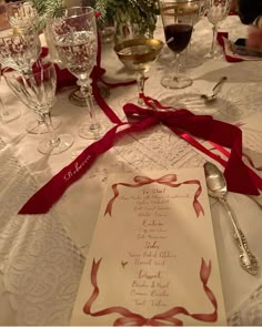 the table is set with wine glasses, silverware and a menu for an event