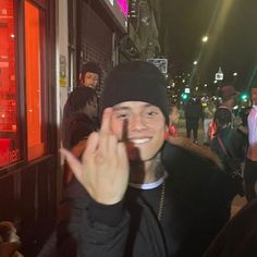 a man is making the peace sign in front of some people on a street at night