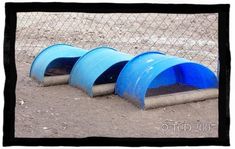 three blue buckets sitting on the ground in front of a chain link fence