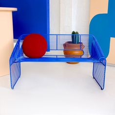 a blue shelf with two pots and a red ball on it in front of a white wall