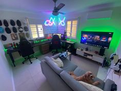 a dog laying on a couch in front of a flat screen tv and gaming room