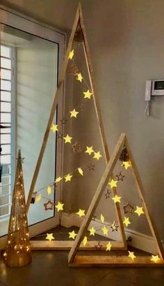 three wooden christmas trees with yellow stars on them and one is lit up in the shape of a triangle