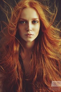 a woman with long red hair and blue eyes