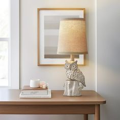 an owl lamp sitting on top of a table next to a book and coffee cup