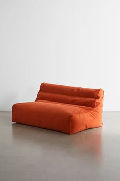 an orange couch sitting on top of a cement floor