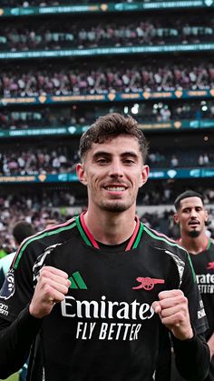 a man standing in front of a crowd wearing a soccer uniform and holding his fist up