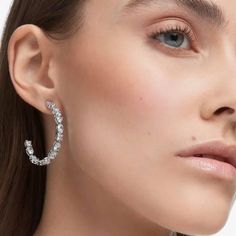 The Swarovski Mesmera Hoop Earrings are a unique design featuring an alluring, partially encrusted hoop adorned with white Swarovski crystals in an array of mixed cuts, ensuring they shimmer from every angle. The rhodium-plated finish adds a touch of timeless allure, making them an essential addition to your collection for both casual and upscale occasions. Elevate your ensemble with a dash of modern allure, as these Mesmera Hoop Earrings effortlessly become a distinctive showcase of your bold and magnetic charm. Size: 3.9 x 0.3cm Weight (individual piece): 4.6g Item Code: 5672834 White Stones, Alloy Earrings, Pierced Jewelry, Swarovski Earrings, Swarovski Jewelry, Bracelet Collection, Pierced Earrings, Trendy Jewelry, Polish Jewelry