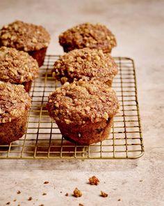 several muffins cooling on a wire rack with some nuts scattered around them,