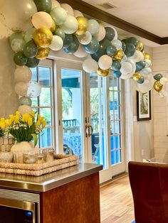 balloons and flowers are hanging from the ceiling above a kitchen counter in front of an open door