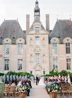 an outdoor ceremony in front of a large building with lots of people sitting on chairs