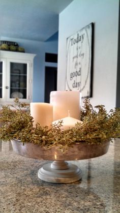 some candles are sitting in a bowl on a counter top with moss growing out of it