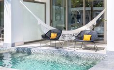 two chairs and a hammock sitting next to a swimming pool