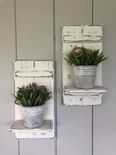 two metal buckets with plants in them are hanging on the wall next to each other