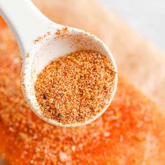 a wooden spoon filled with spices on top of a table