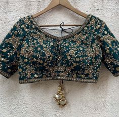 A three-piece green sharmily lehenga set from the Priti Sahni collection. This beautiful forest green georgette lehenga with sequin butti all over and zari scallop work border is paired with a green sequin, beads & zardozi hand-embroidered blouse. The lehenga has side hanging ball tassels to the waistline. And the blouse has a ghungroo tassel tie-up at the back. This outfit is completed with a nude sequined work net dupatta. Green Chinon Choli With Resham Embroidery, Green Lehenga With Unstitched Blouse In Chinon, Designer Green Chinon Choli, Festive Green Chinon Lehenga, Green Lehenga With Intricate Embroidery In Chinon, Green Chinon Lehenga With Intricate Embroidery, Green Lehenga With Dori Work In Chinon, Green Chinon Lehenga For Reception, Embroidered Green Chinon Choli