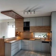 a modern kitchen with wooden accents and white cabinets is pictured in this image, there are lights hanging from the ceiling