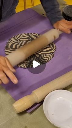 a person rolling dough on top of a purple mat