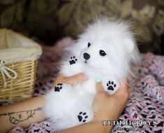 a person holding a white stuffed animal with black paws on it's fingers and feet