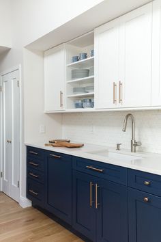 a kitchen with blue cabinets and white counter tops, gold pulls on the cupboards