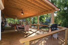 a covered deck with grill and table on it