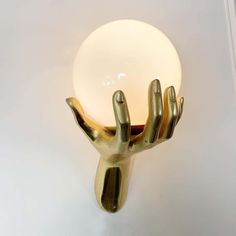 a light that is sitting on top of a white wall mounted fixture with two hands reaching for it