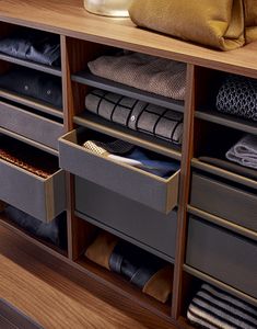 an organized closet with drawers and folded clothes on the bottom shelf next to a purse