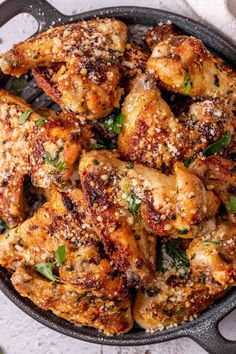 chicken wings with herbs and seasoning in a cast iron skillet on a white surface