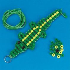 a green and yellow beaded lizard next to some beads