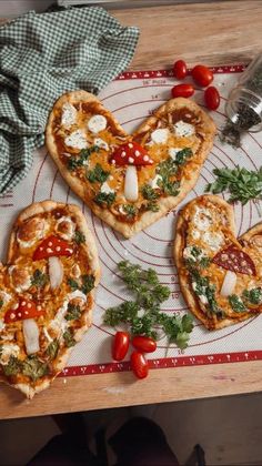 three heart shaped pizzas sitting on top of a table