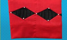 a red piece of fabric with black and white stitching on it, next to a blue background