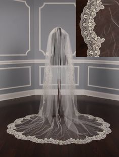 a white veil on top of a wooden floor in front of a wall with a mirror