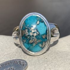 Make a statement with this stunning Persian Turquoise oval cabochon ring, displaying rich colours with inclusions of sparkly cubic pyrite! It has been beautifully set into a 925 sterling silver surround with an adjustable band, which sits comfortably on the finger. Originally called 'piruzeh' in Persian, the gem has spiritual value in Persian culture is such that its name carries the meanings of victory, triumph, and prosperity. Turquoise is an opaque, blue-to-green phosphate mineral and has bee Oval Silver Chrysocolla Turquoise Ring, Oval Turquoise Chrysocolla Ring In Silver, Untreated Chrysocolla Turquoise Ring In Silver, Pyrite Ring, Turquoise Jewellery, Persian Turquoise, Handmade Sterling Silver Rings, Persian Culture, Real Turquoise