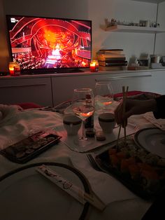 a person sitting at a table with food and drinks in front of a flat screen tv