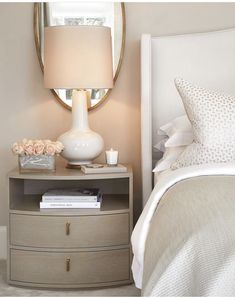 a bedroom with a bed, nightstand and round mirror on the wall above it's headboard