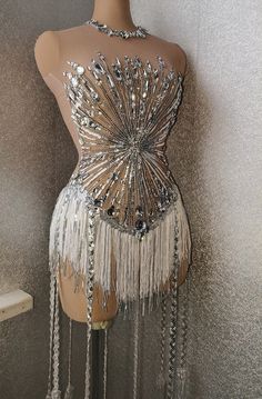 a mannequin is adorned with silver beads and fringes on it's back