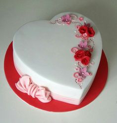 a heart shaped cake decorated with pink and red flowers